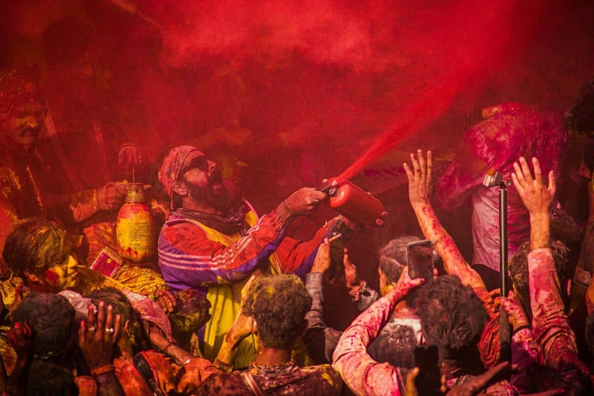 Devotees celebrating Holi with clouds of red powder in a joyful crowd